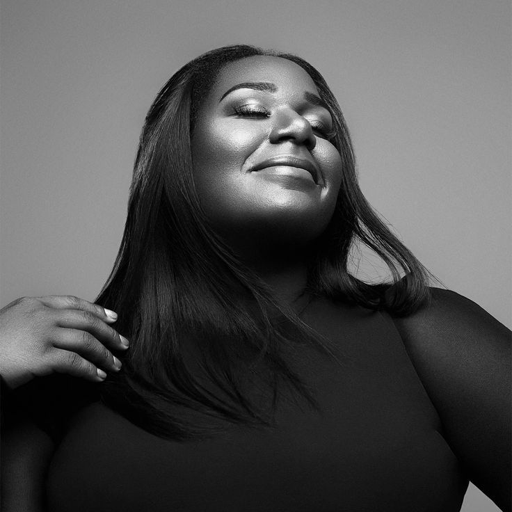 Black-and-white studio portrait of Naomi Raine, eyes closed, smiling